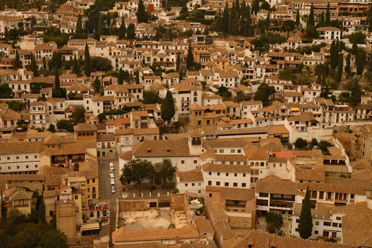 วิวทิวทัศน์ของย่าน Albaicín ในเมือง Granada แสดงให้เห็นกลุ่มบ้านฉาบปูนสีขาวหนาแน่นที่มีหลังคากระเบื้องบนเนินเขา