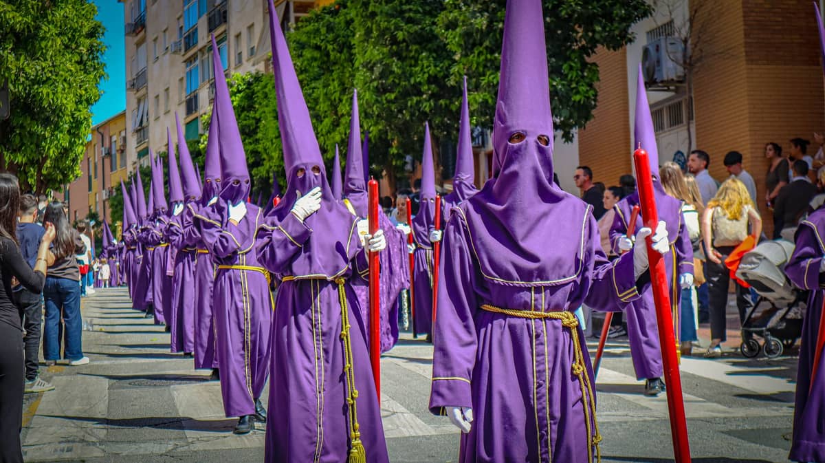 ขบวนแห่ Semana Santa ในเมือง Granada โดยมีผู้คนสวมชุดคลุมสีม่วงแบบดั้งเดิมและหมวกทรงแหลมสูง เดินผ่านถนนในเมือง