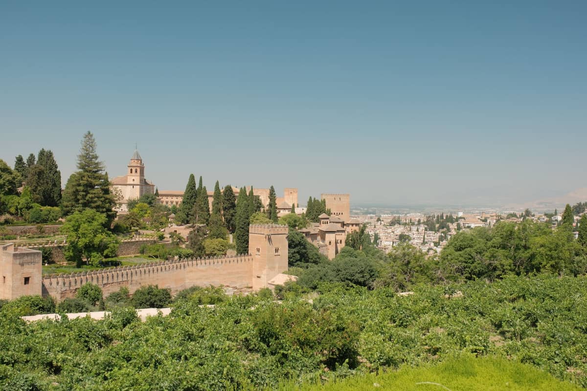 วิวภูมิทัศน์กว้างจากเนินเขา Alhambra แสดงให้เห็นกำแพงป้อมปราการ หอคอย สวนสีเขียว และทัศนียภาพอันกว้างไกลเหนือเมือง Granada