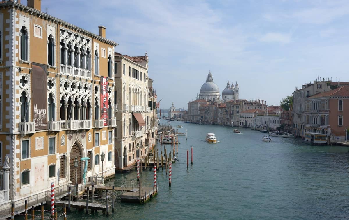 Blick tagsüber entlang des Canal Grande in Venedig mit historischen Palästen auf beiden Seiten und der Kuppel der Basilica di Santa Maria della Salute in der Ferne.