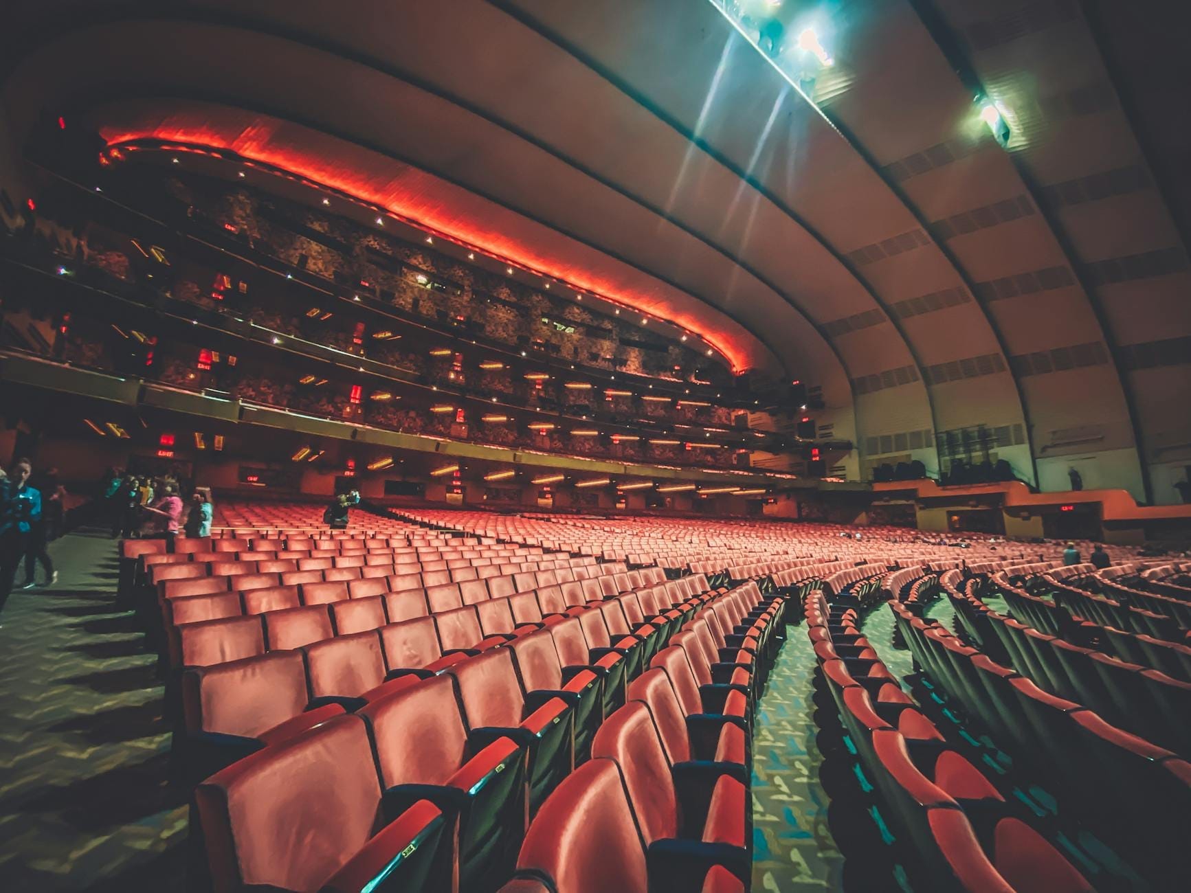 Vista gran angular de un gran auditorio moderno con asientos rojos y balcones de varios niveles, mostrando la distribución del aforo y la arquitectura.