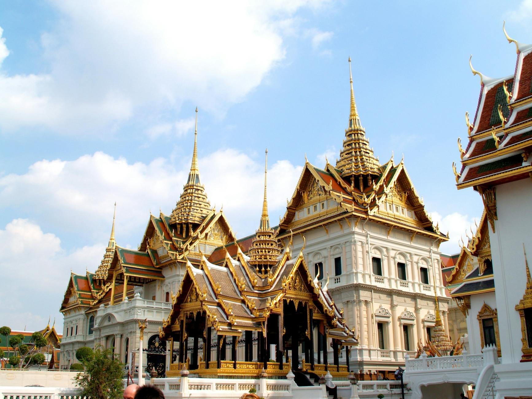 Complesso principale del Grand Palace di Bangkok con edifici dorati riccamente decorati e guglia centrale sotto un cielo azzurro