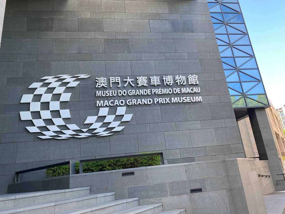 Eingang des Macao Grand Prix Museums mit großem Schriftzug auf Englisch, Chinesisch und Portugiesisch an einer modernen Steinfassade.