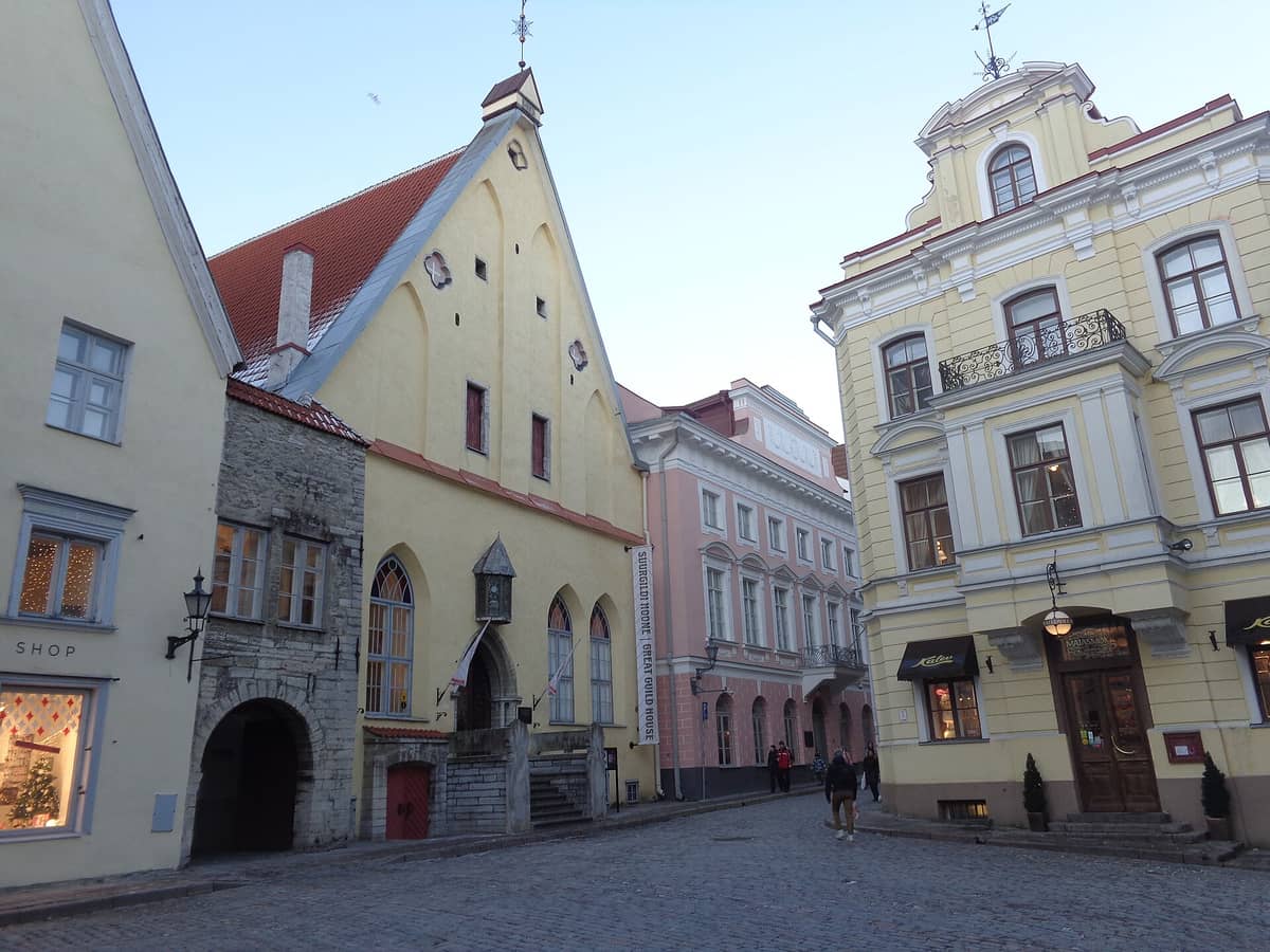 Blick von der Straße auf die gotische Fassade der Großen Gilde in Tallinn mit ihrem Rundbogenportal, den Steinstufen und den historischen Nachbargebäuden an der Pikk.