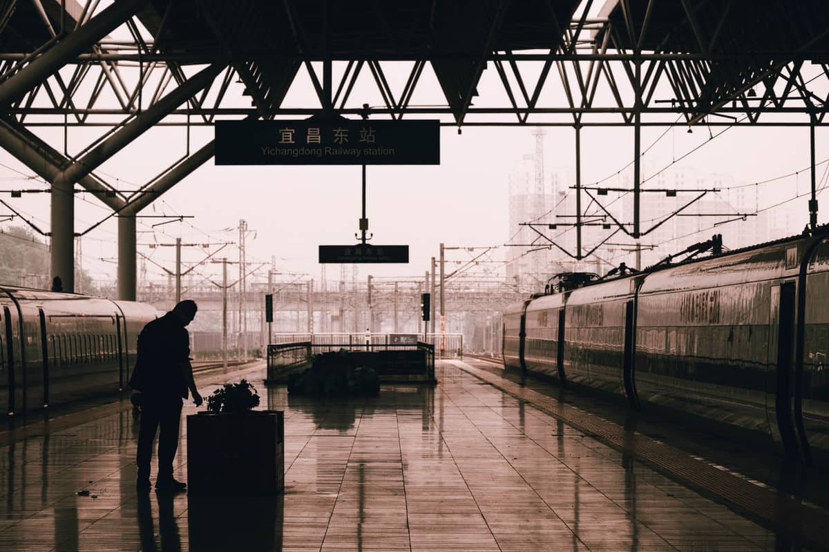 Tren de alta velocidad chino en el andén de una estación de ferrocarril moderna con un pasajero y señalización en chino