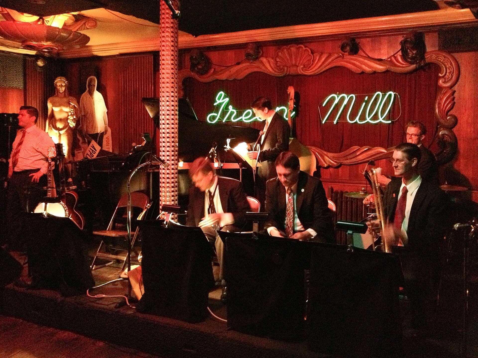 Una band jazz si esibisce sul palco dello storico Green Mill Cocktail Lounge di Chicago, immersa in luci calde e arredi classici.