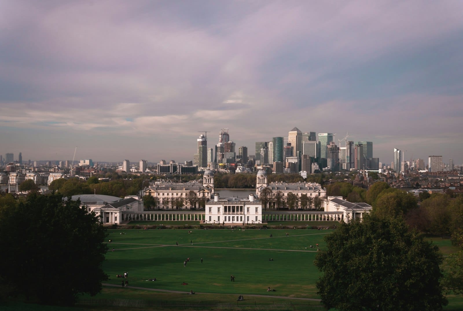 วิวพาโนรามาของสวนกรีนิช ควีนส์เฮาส์ และ Old Royal Naval College พื้นหลังคือ Canary Wharf ยามเย็นท้องฟ้าหลากสี