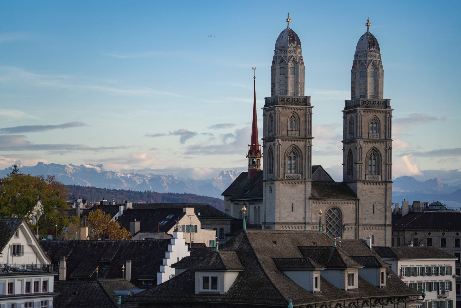 โบสถ์ Grossmünster กับหอคอยคู่เด่น แลนด์มาร์กกลางเมืองเก่าซูริคที่เห็นยอดเขาแอลป์เป็นฉากหลังในวันที่ฟ้าใส