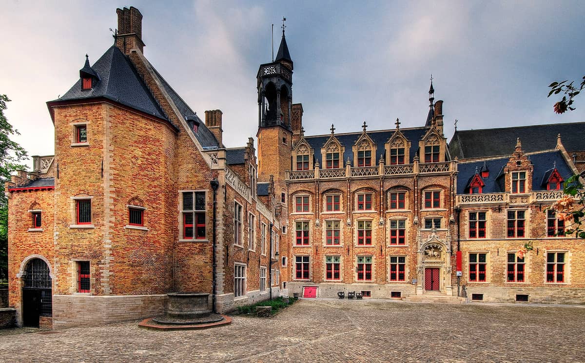 The main courtyard of the Gruuthuse Museum in Bruges, showing the ornate medieval brick palace facade with red-framed windows and architectural details.