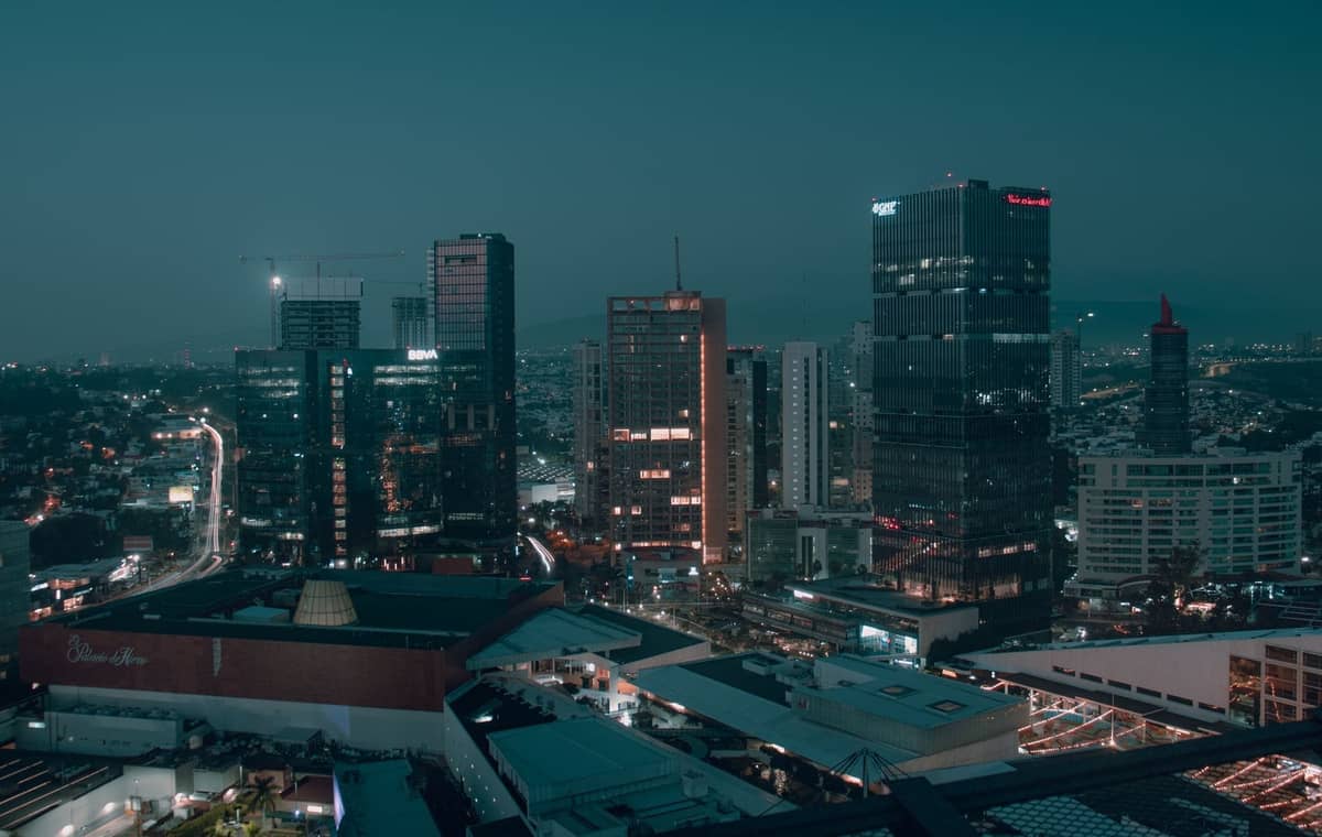 Nächtliche Ansicht moderner Hochhäuser und Glastürme im Andares-Viertel von Guadalajara, mit einer lebhaften zeitgenössischen Skyline und Stadtlichtern.