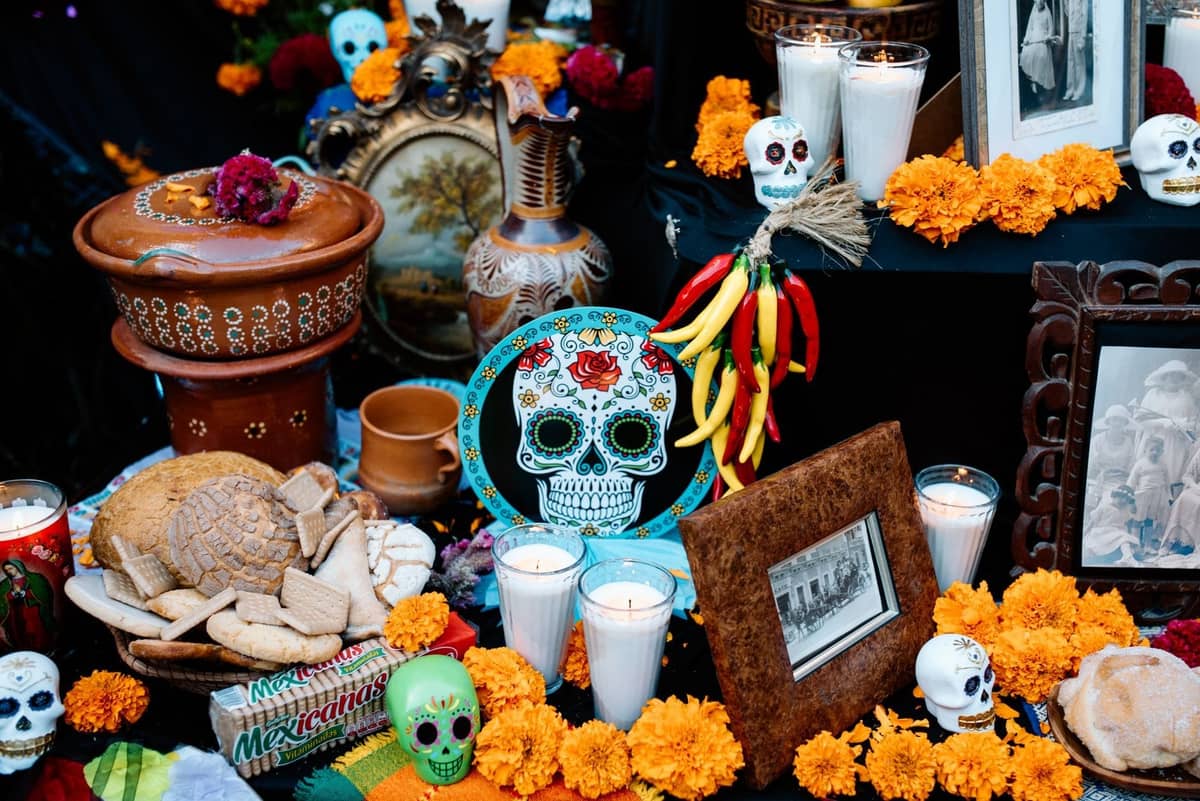 Día de los Muertos-Altar mit Ringelblumen, Brot, Kerzen, Zuckerschädeln, gerahmten Fotos und traditioneller Keramik in Guadalajara.