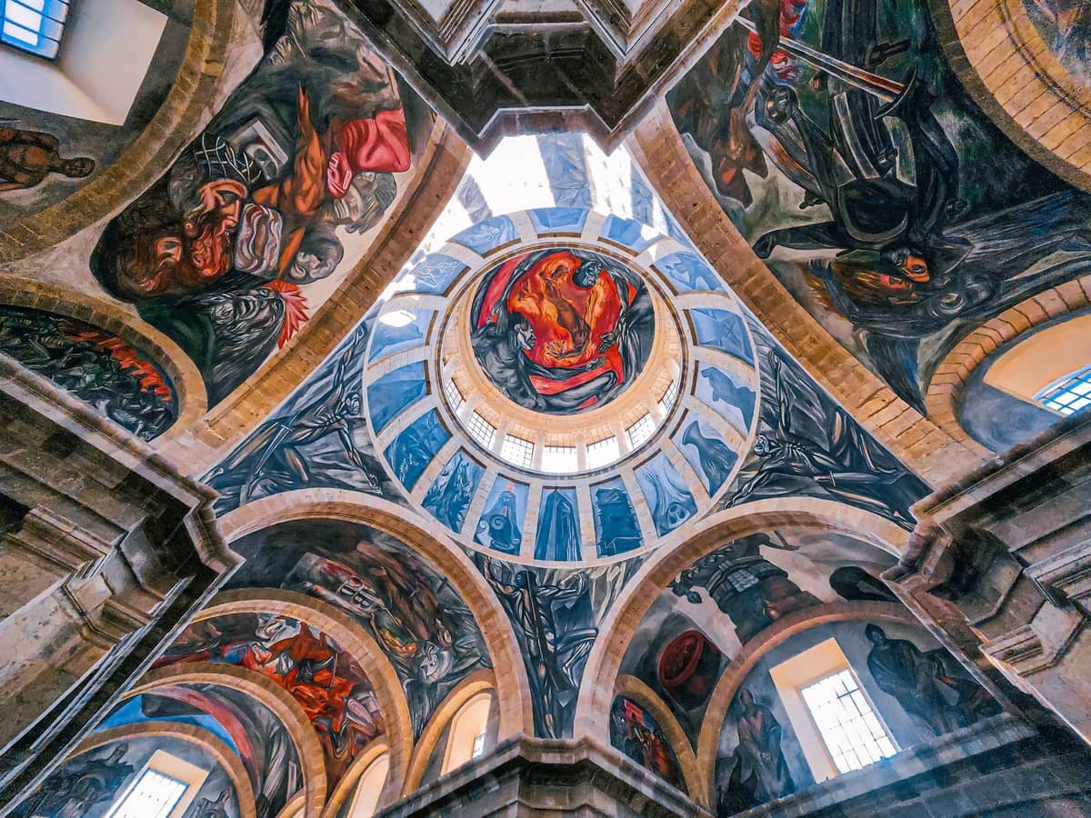 Lebendige Innenansicht einer großen Rotunde mit dramatischen Wandgemälden an der Decke und Bögen, in natürliches Licht getaucht in einem historischen Museum.