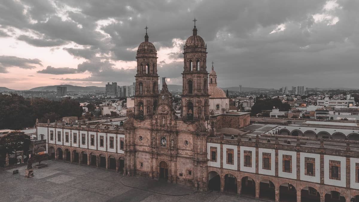 Luftaufnahme des historischen Platzes und der Kathedrale in der Innenstadt von Guadalajara mit dramatischen Wolken darüber.