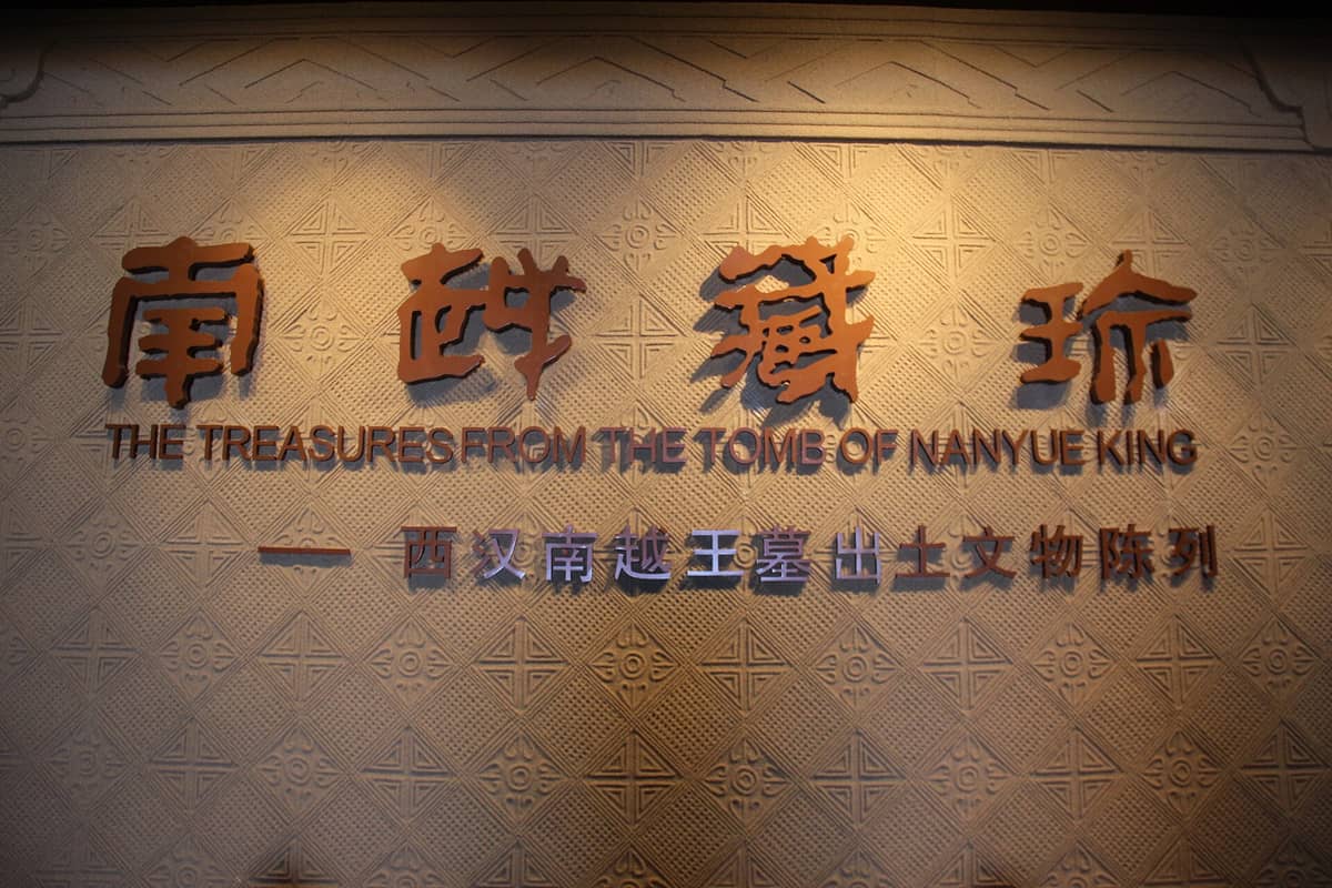Parede com a inscrição 'The Treasures from the Tomb of Nanyue King' em chinês e inglês no interior do museu da tumba em Guangzhou.