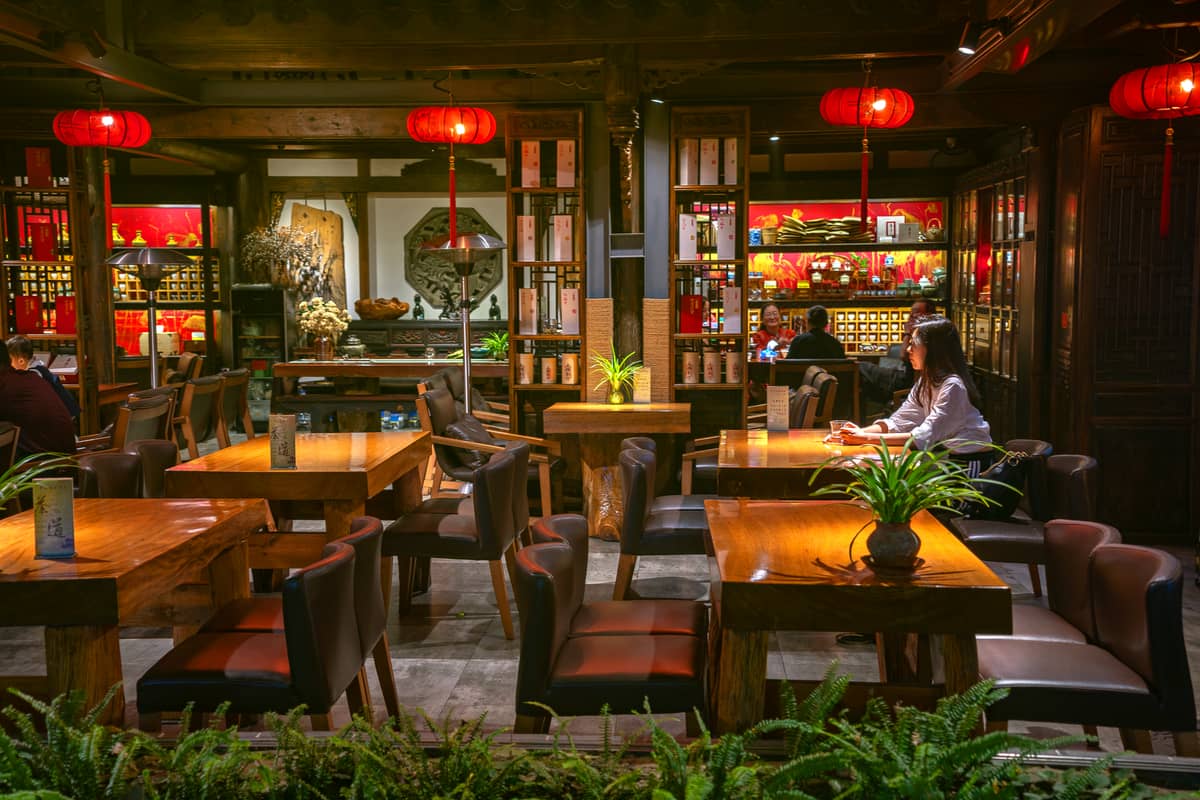 Interior of a traditional Chinese tea house in Guangzhou, with wooden tables, red lanterns, and a relaxed, social atmosphere.