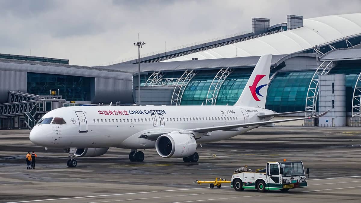 China Eastern airplane on the tarmac in front of the modern terminal building at Guangzhou Baiyun International Airport under cloudy skies.