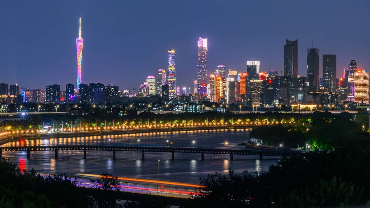 Guangzhou's illuminated skyline at night with the colorful Canton Tower and modern skyscrapers reflecting over the Pearl River.