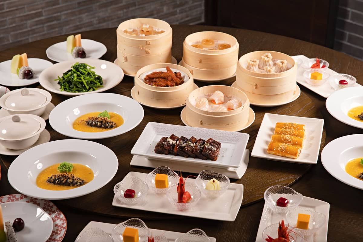 A luxurious Cantonese banquet table set with dim sum baskets, plated desserts, braised dishes, and elegant appetizers in a fine dining Guangzhou restaurant.