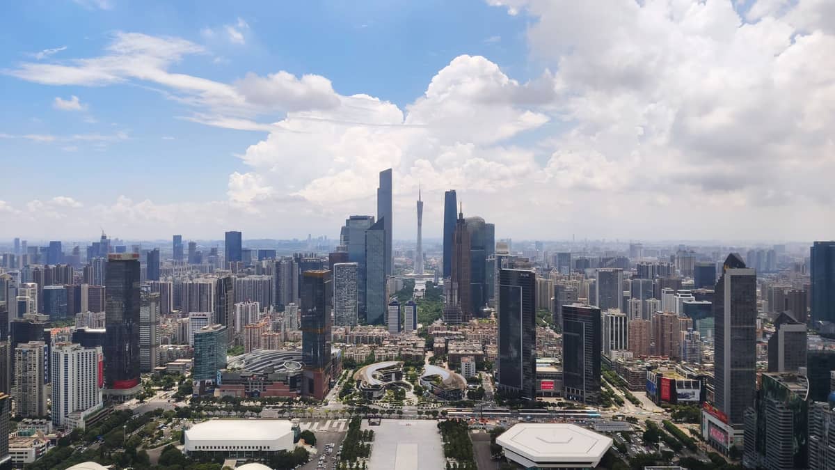 Aerial view of Guangzhou showing multiple business districts with modern skyscrapers, urban streets, and distinct clusters of commercial activity on a clear day.