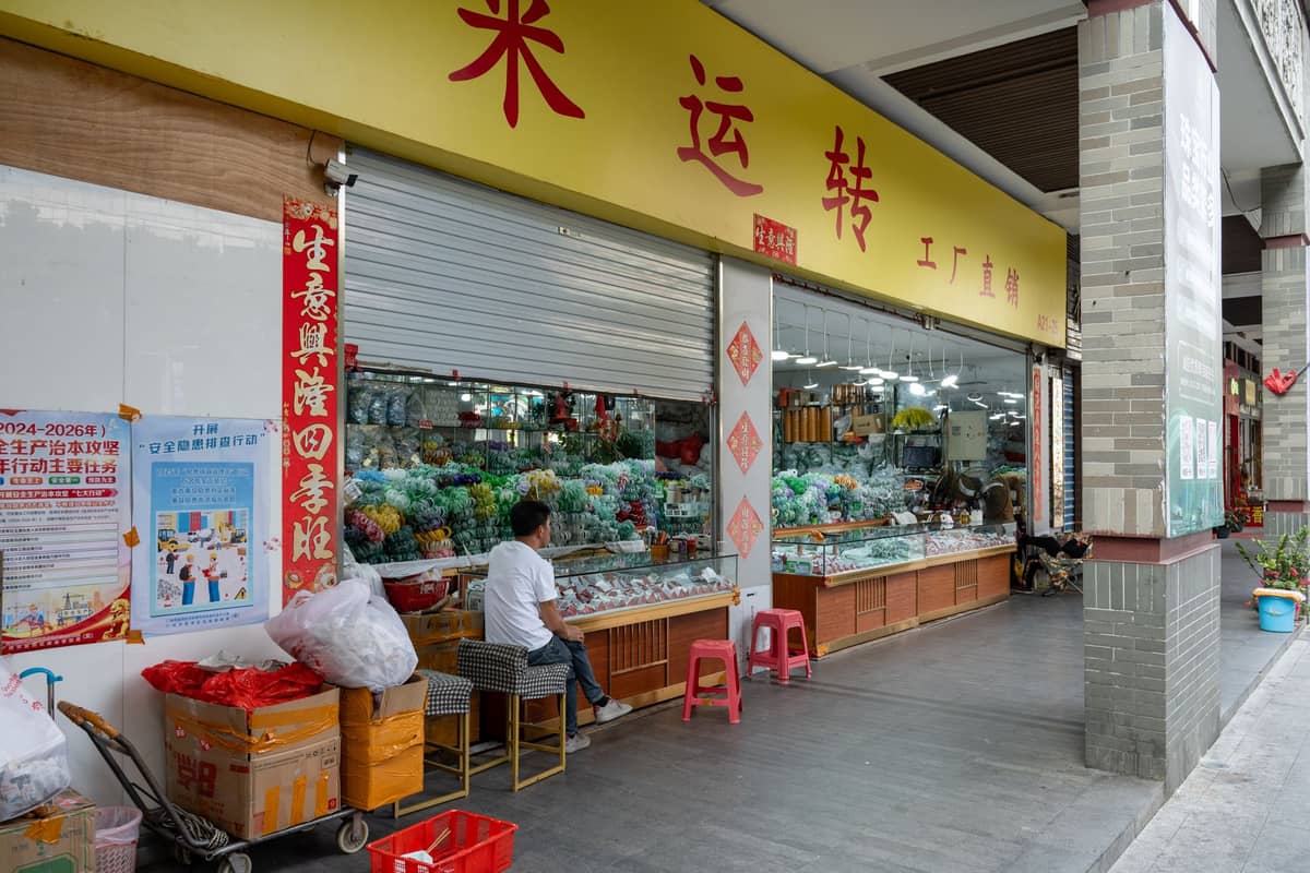 Exterior view of a specialty jade and jewelry market shop in Guangzhou, with people sitting outside and goods visible through the window.
