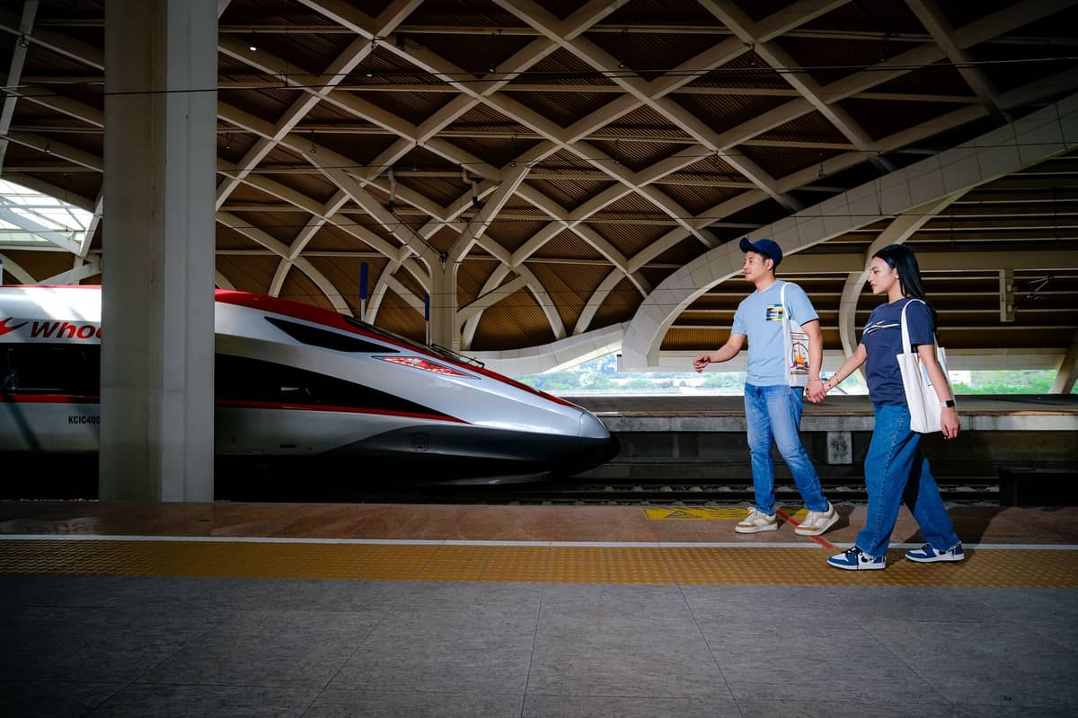 Two people walk on a high-speed train platform in China with a modern bullet train at the station.