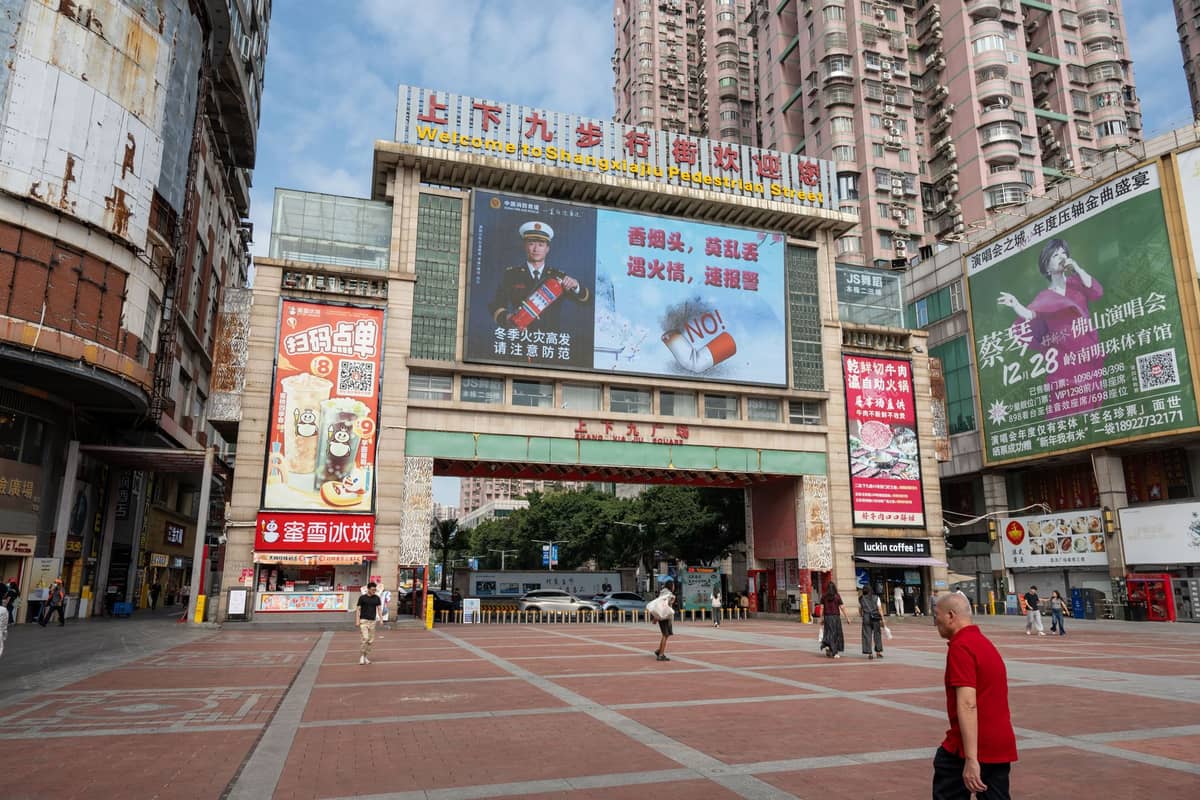 Large entrance gate of a wholesale market complex in urban Guangzhou, with people walking and tall apartments in background.