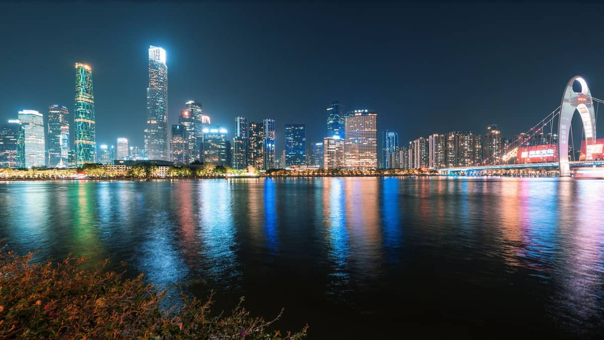 Guangzhou skyline and iconic Liede Bridge at night, reflecting colorful lights on the Pearl River with modern skyscrapers in the background.