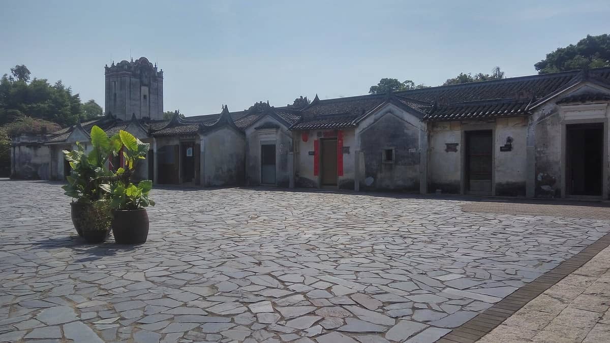 Antigas casas hakka na Aldeia Internacional de Impressão de Guanlan, Shenzhen, alinhadas em um pátio de pedra sob um céu azul claro.
