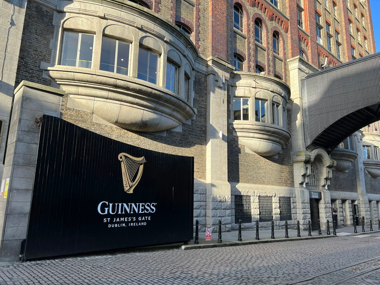 Vista esterna del Guinness Storehouse a St James's Gate a Dublino, con l'iconico ingresso, la facciata in mattoni storici e il selciato.