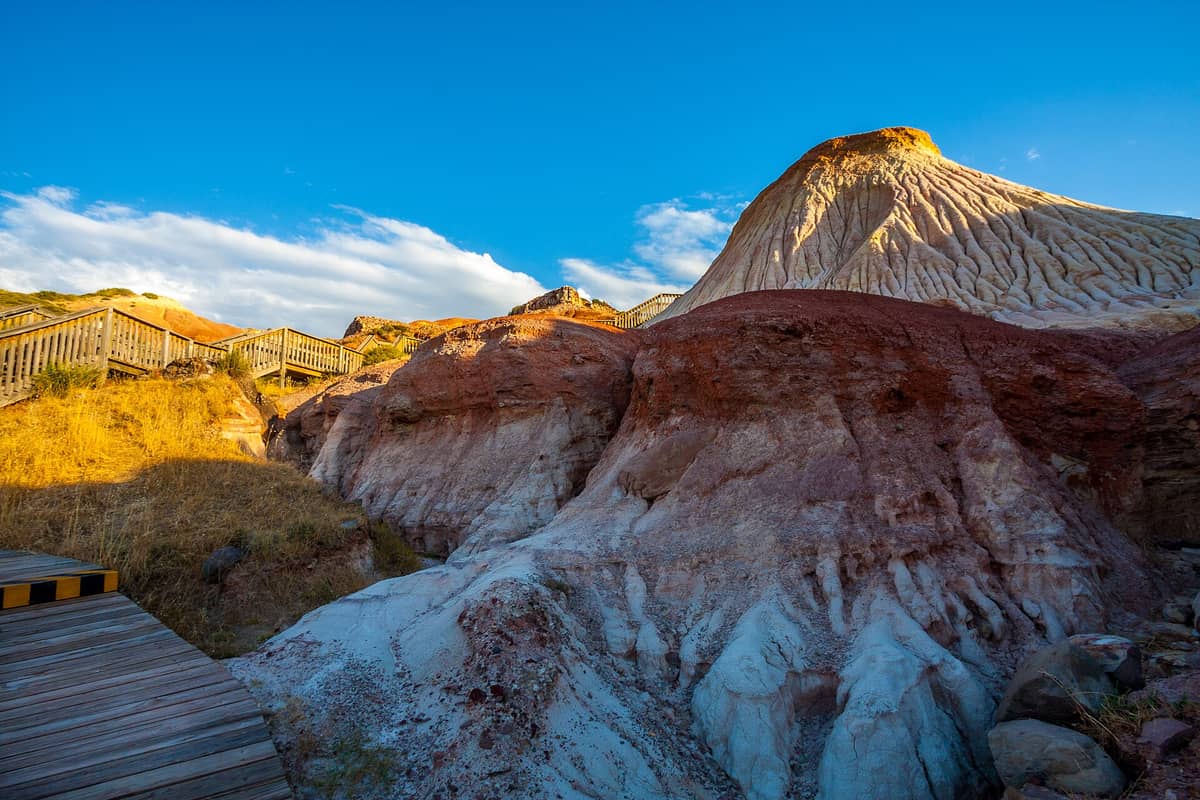 Boardwalk and dramatic red and white glacial rock formations at Hallett Cove Conservation Park under a clear blue sky.