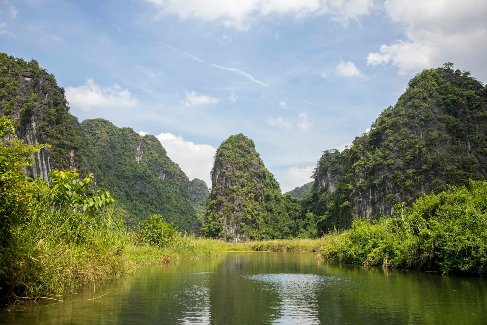 River winding through lush green karst mountains under blue sky in Ninh Binh, a popular day trip from Hanoi