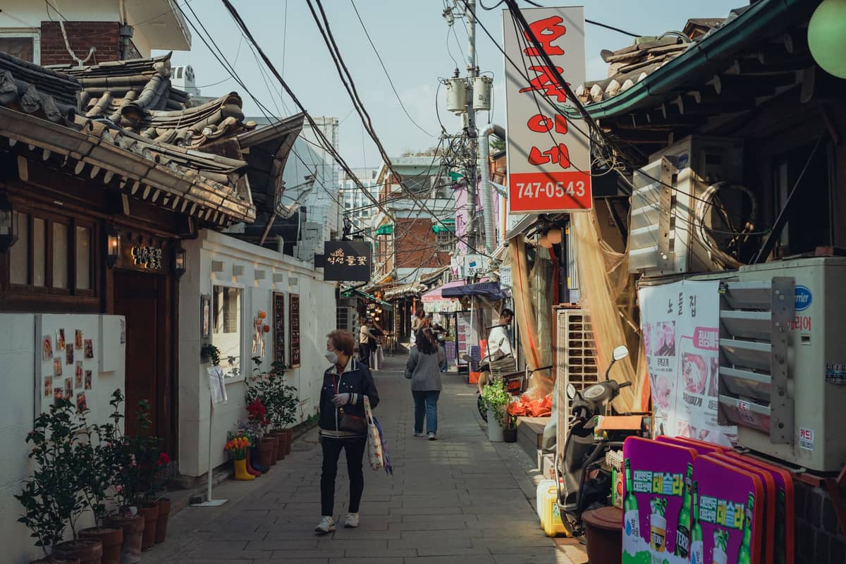 Beco estreito em Seul repleto de telhados hanok, lojas independentes e letreiros coloridos, capturando o clima dos bairros de Seochon ou Ikseon-dong.