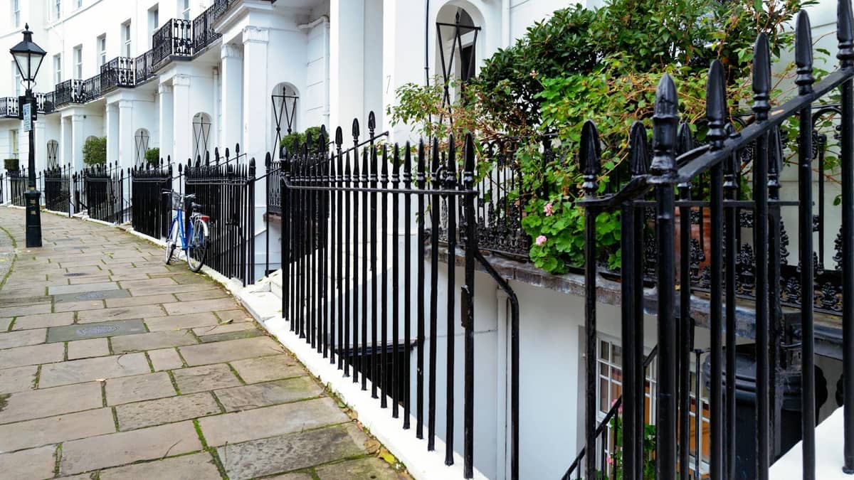 Uma fila georgiana de casas geminadas brancas com grades de ferro forjado preto e uma tranquila praça ajardinada em Londres.