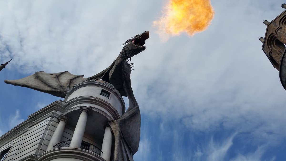 Ein feuerspeiender Drache, der auf der Gringotts Bank in der Diagon Alley in den Universal Studios Florida sitzt, umgeben von aufwendig gestalteten Gebäuden der Zauberwelt.