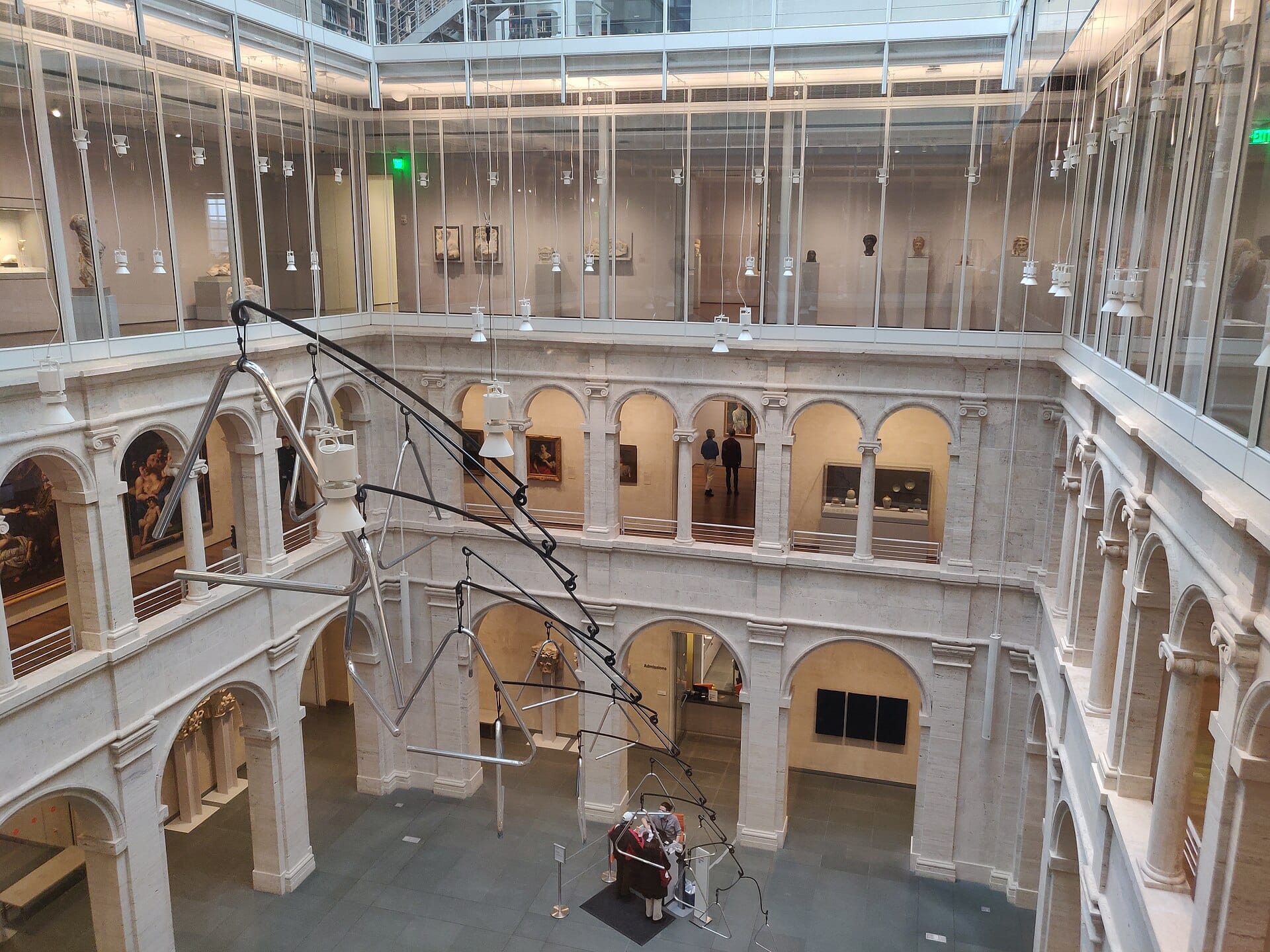 Il cortile centrale degli Harvard Art Museums presenta gallerie ad arco in pietra, pareti di vetro e una grande scultura contemporanea sospesa sotto soffitti illuminati da lucernari.