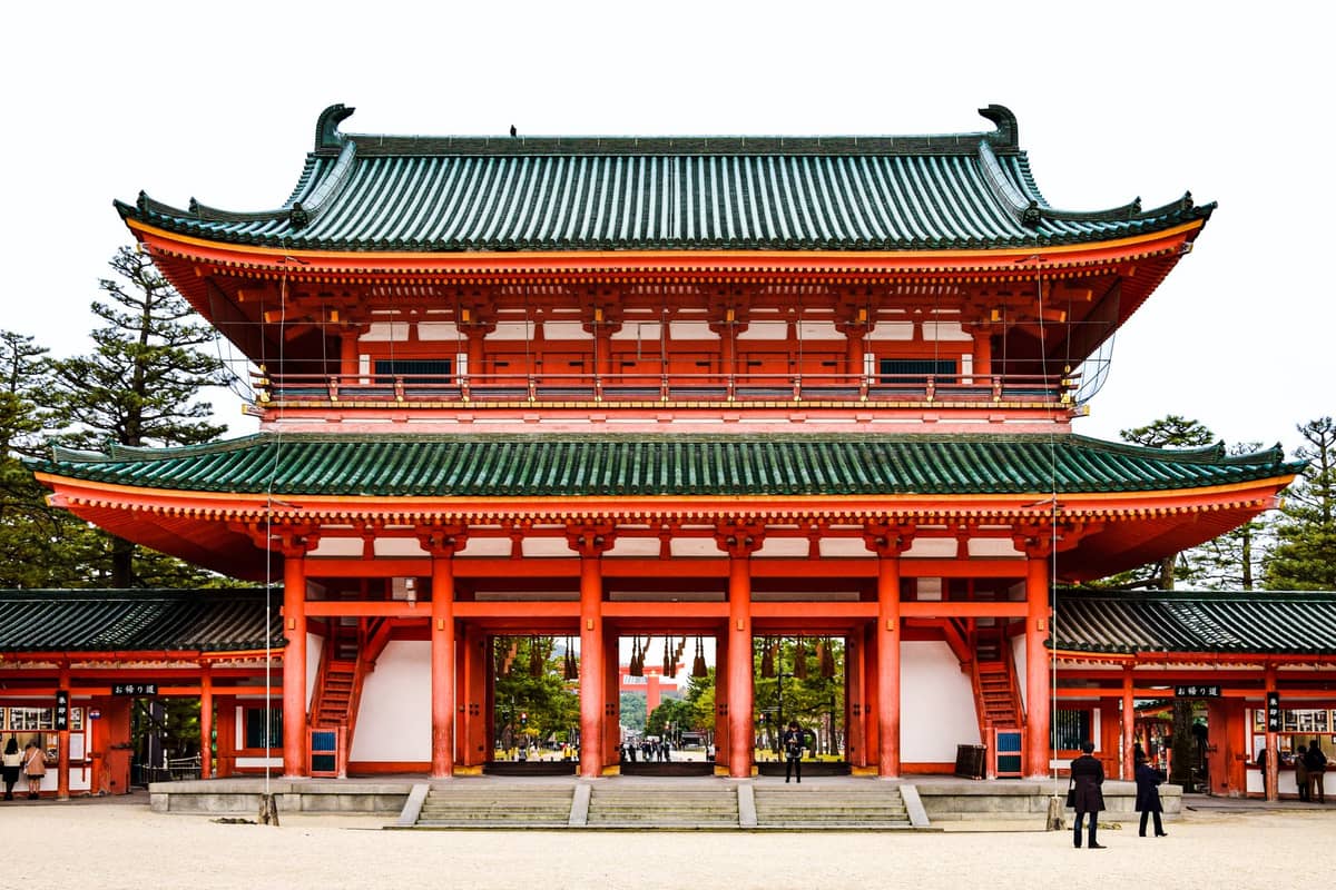 The imposing Otenmon main gate of Heian Jingu Shrine in Kyoto, with its signature bright red pillars and green tiled roof, seen from the front.