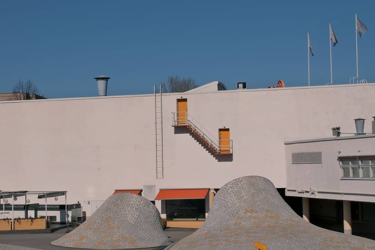 Vista ampla da praça Amos Rex com distintas claraboias em forma de cúpula emergindo do chão e fachada modernista branca.