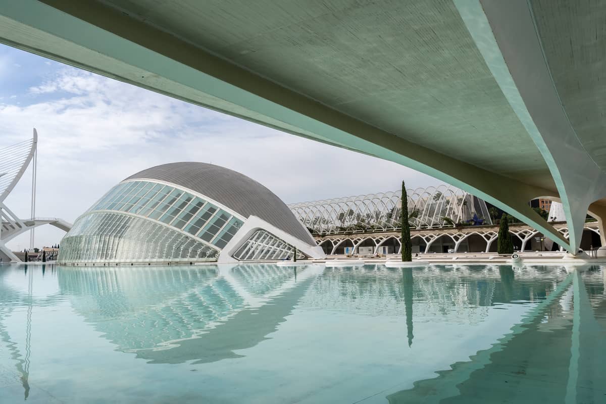 Vista orizzontale dell'Hemisfèric a Valencia: la sua iconica struttura in vetro a forma di occhio si riflette nell'acqua blu della Città delle Arti e delle Scienze.
