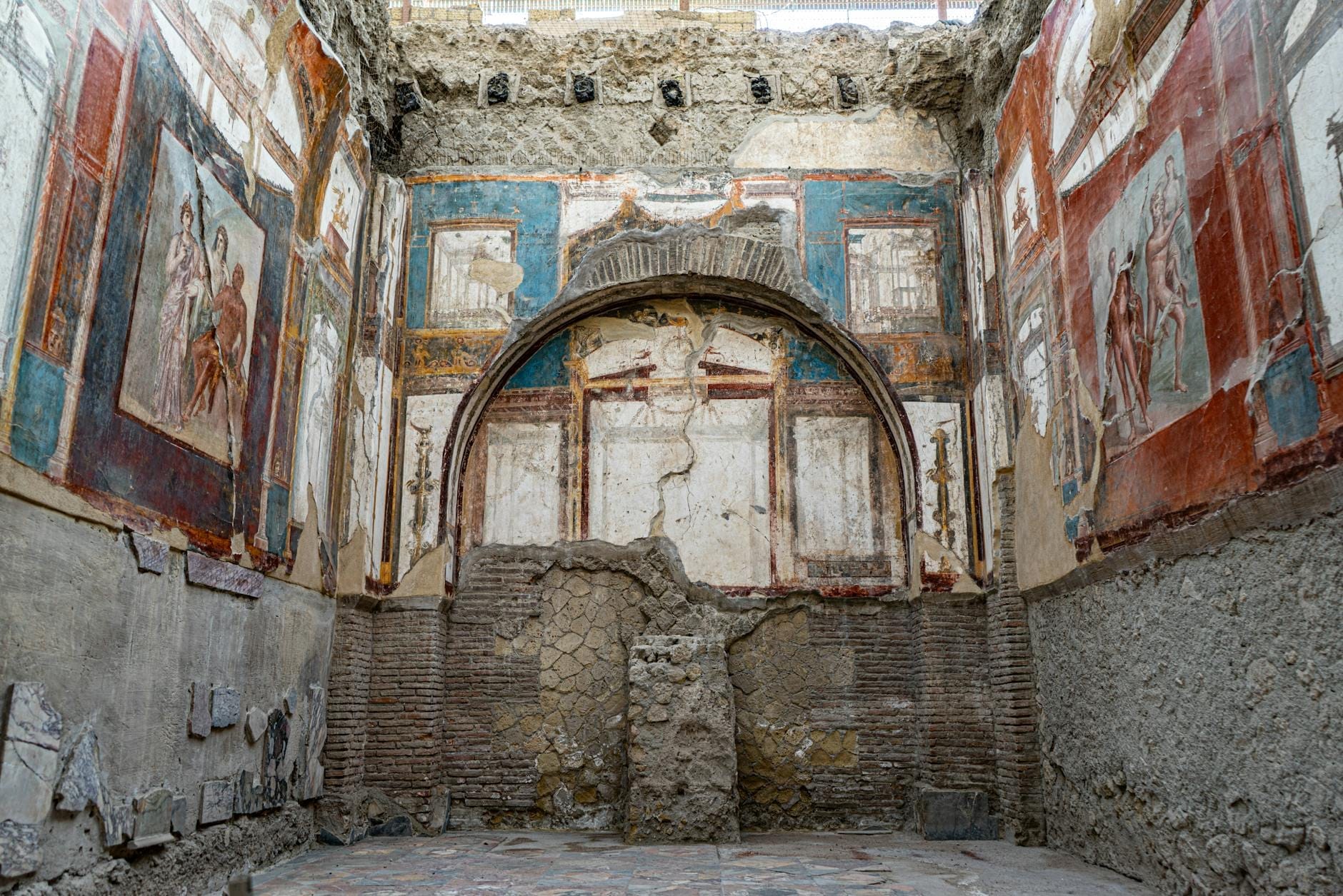 Ambiente romano ad Ercolano con affreschi vivaci e pitture parietali dettagliate, testimonianza dell'arte e dell'architettura ben conservate della città.