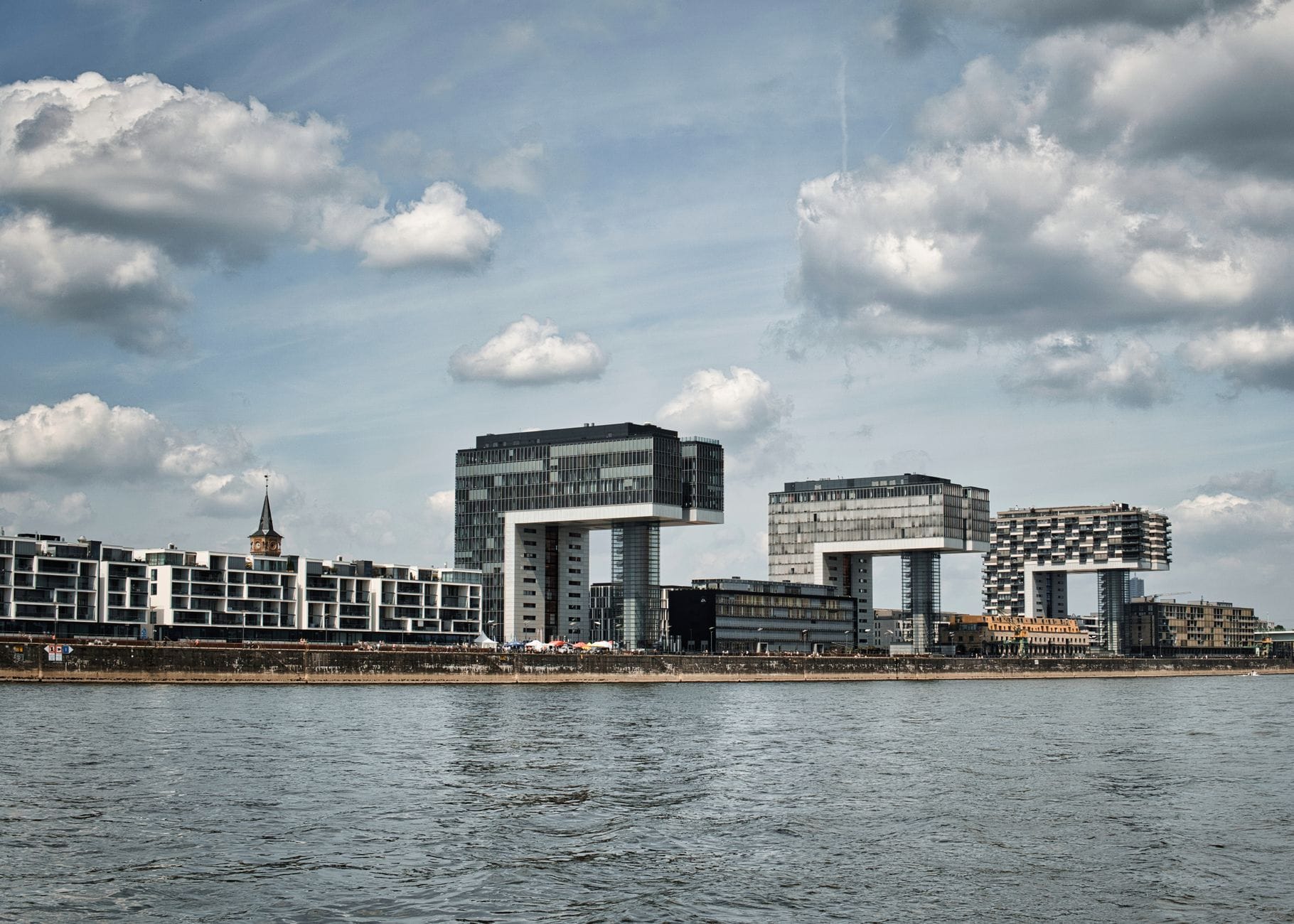 วิวพาโนรามาของ Rheinauhafen เมือง Cologne พร้อมบ้านเครนสมัยใหม่ริมแม่น้ำ แสดงให้เห็นสถาปัตยกรรมริมน้ำที่โดดเด่นและวัฒนธรรมเมือง