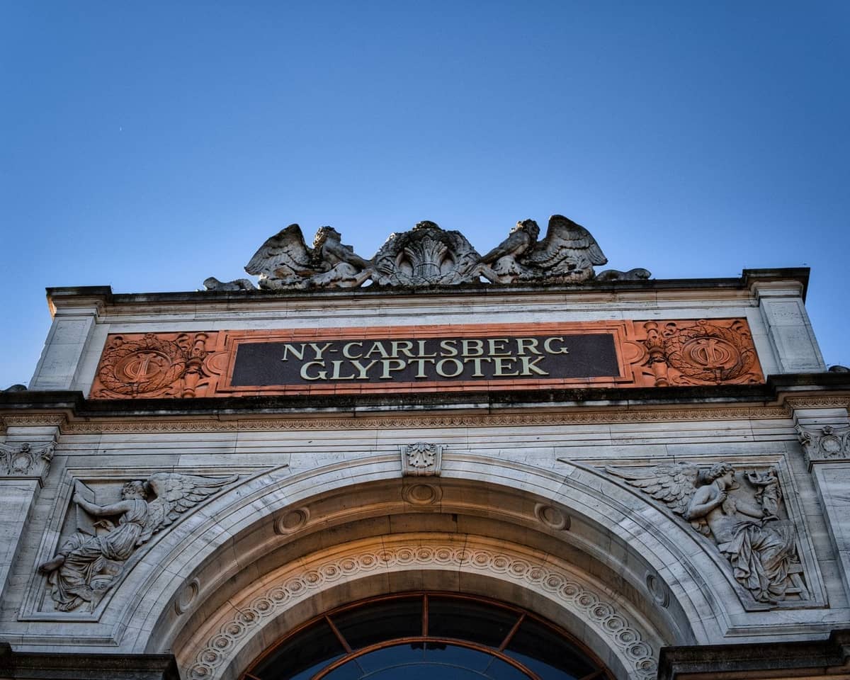 Fasada Ny Carlsberg Glyptotek, renomowanego muzeum sztuki w Kopenhadze, pod bezchmurnym błękitnym niebem