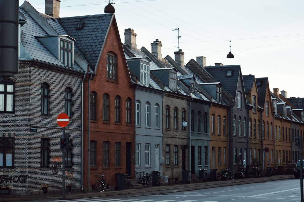 Rząd uroczych, kolorowych budynków mieszkalnych i zaparkowanych rowerów wzdłuż spokojnej ulicy w dzielnicy Copenhagen.