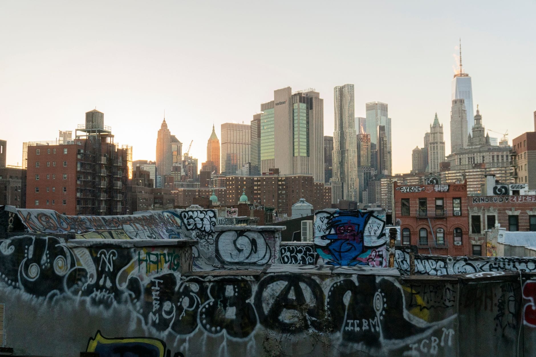 Skyline de Nova York ao pôr do sol com telhados cobertos de grafite em primeiro plano, destacando o lado urbano e alternativo da cidade.