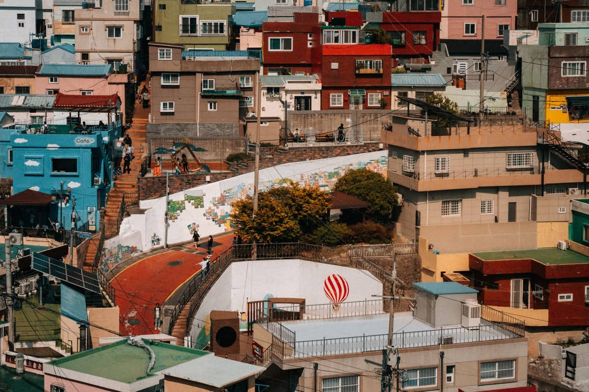 Bairro colorido em encosta com murais, casinhas e uma escadaria em uma área residencial de Seul sob uma luz solar suave.