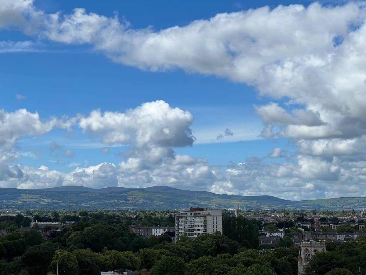Vue panoramique de la ville de Dublin avec les Dublin Mountains en arrière-plan sous un ciel partiellement nuageux.