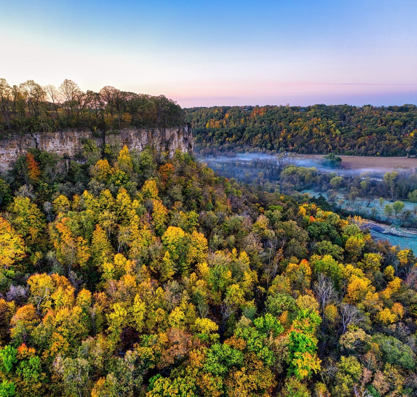 Imponentes acantilados boscosos y vibrantes árboles otoñales sobre un río, típicos de los parques estatales cerca de Nashville, al amanecer o al atardecer.