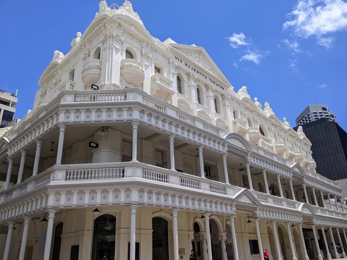 Prachtvolle edwardianische Fassade des His Majesty's Theatre in Perth mit cremefarbenen Balkonen, Säulen und dekorativen Architekturdetails vor strahlend blauem Himmel.