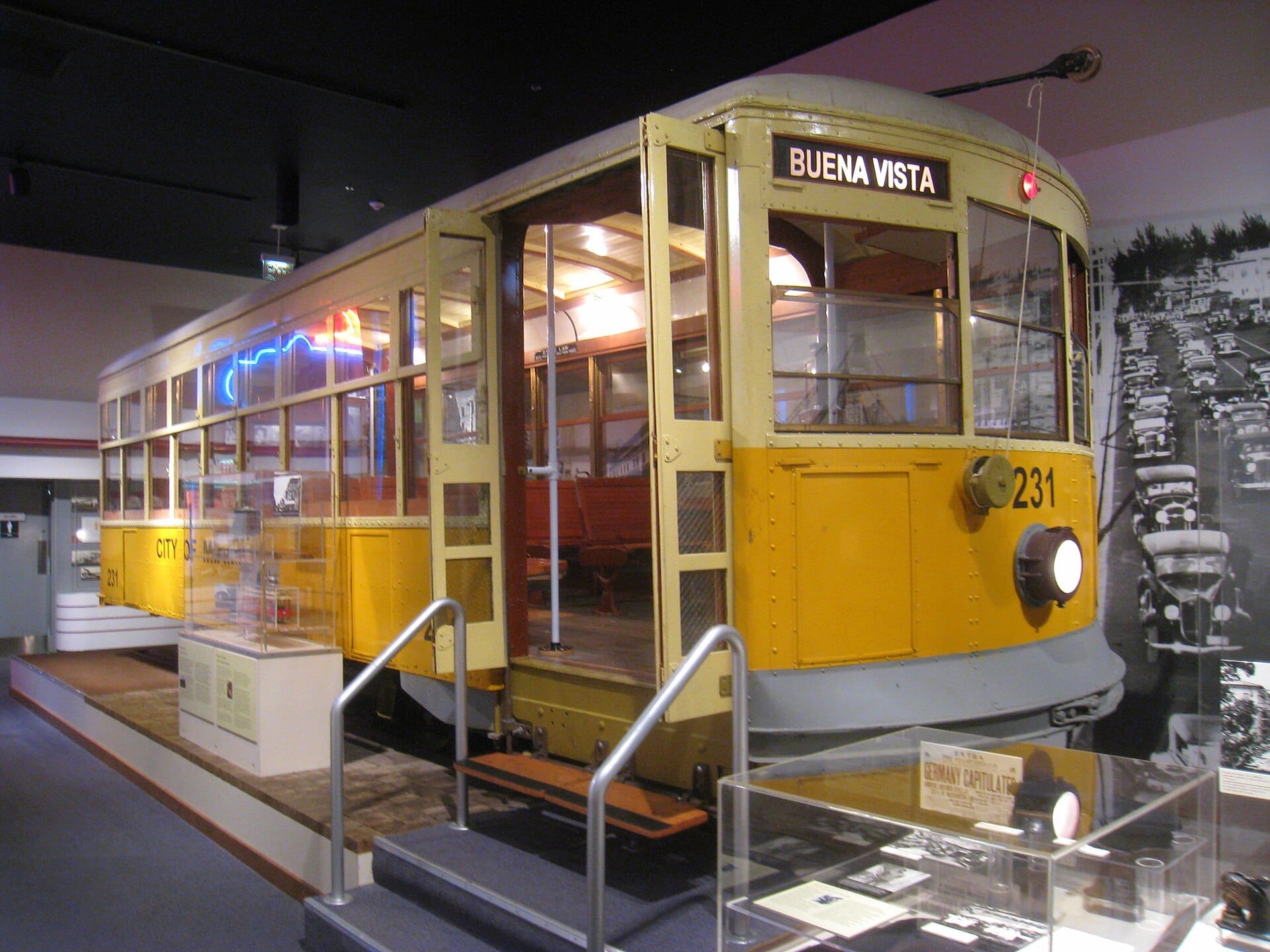 Storico tram giallo in esposizione al Museum of Miami, circondato da foto d'epoca e manufatti in uno spazio espositivo ben illuminato.