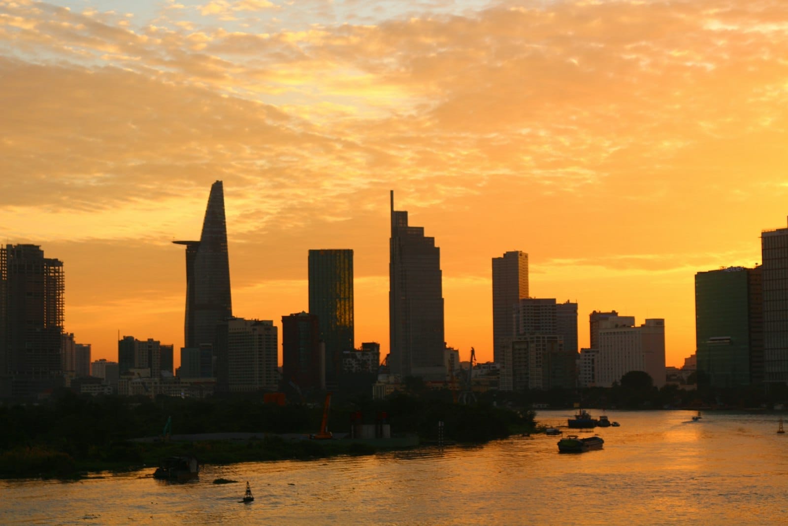 Horizonte de Ho Chi Minh City al atardecer con edificios modernos y el río Saigon en primer plano