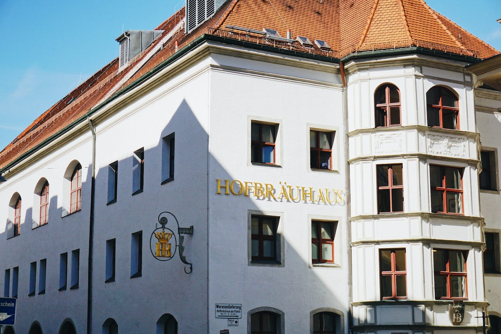 ด้านหน้าของ Hofbräuhaus มิวนิก งดงามด้วยผนังสีขาว ป้ายทอง หน้าต่างเรียงหลายบาน ท่ามกลางแสงแดดอ่อน